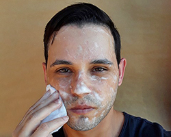 A young man washing his face with a scrubber